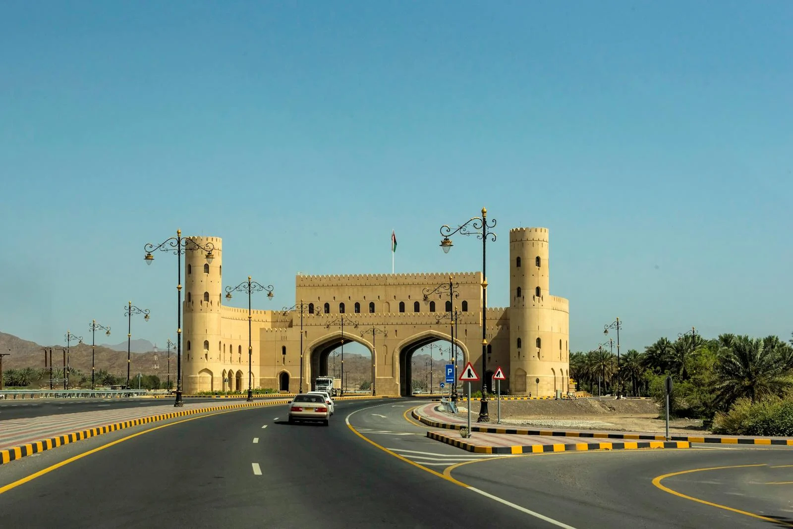 Photo by Frans van Heerden A traditional Omani gateway viewed from the road under clear blue skies.