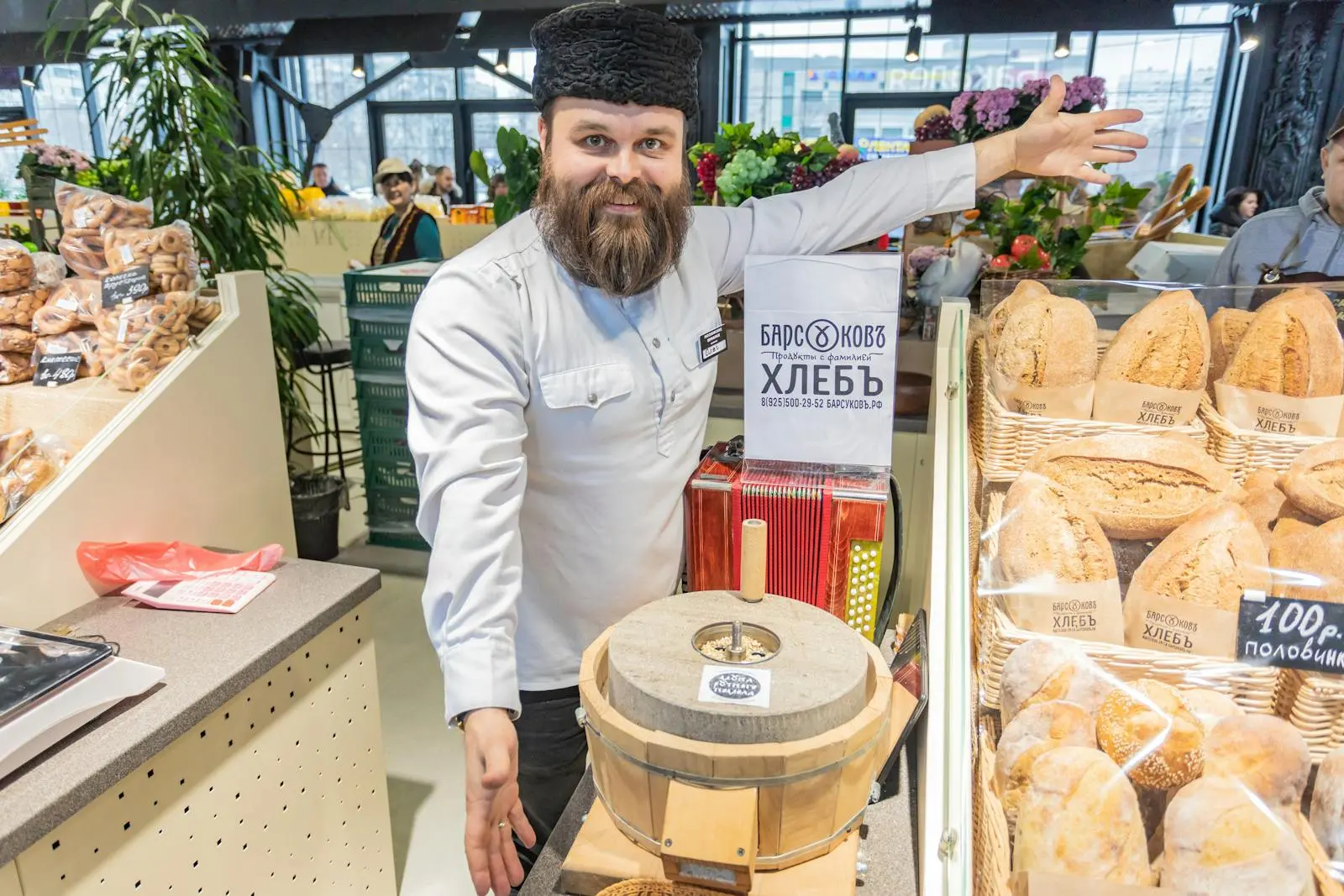Cheerful baker presenting freshly baked bread in a Moscow bakery, showcasing natural ingredients and traditional methods.