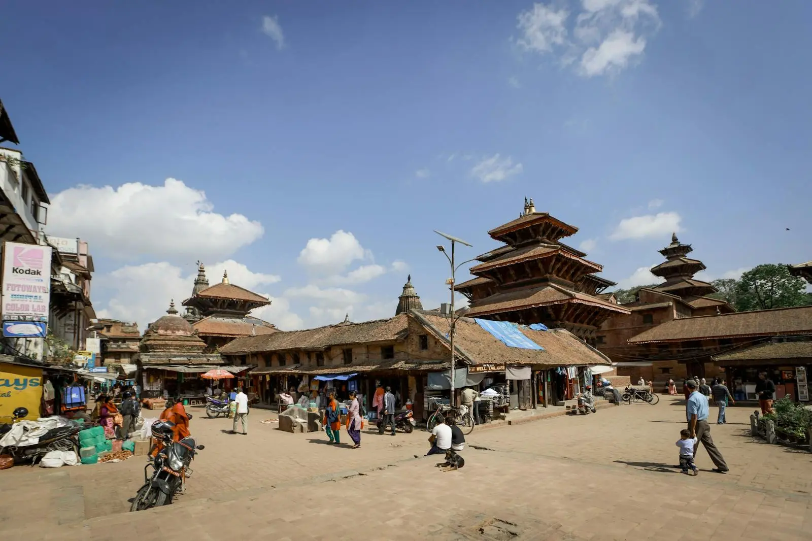 Vibrant market scene filled with people and historic temples under a clear blue sky.