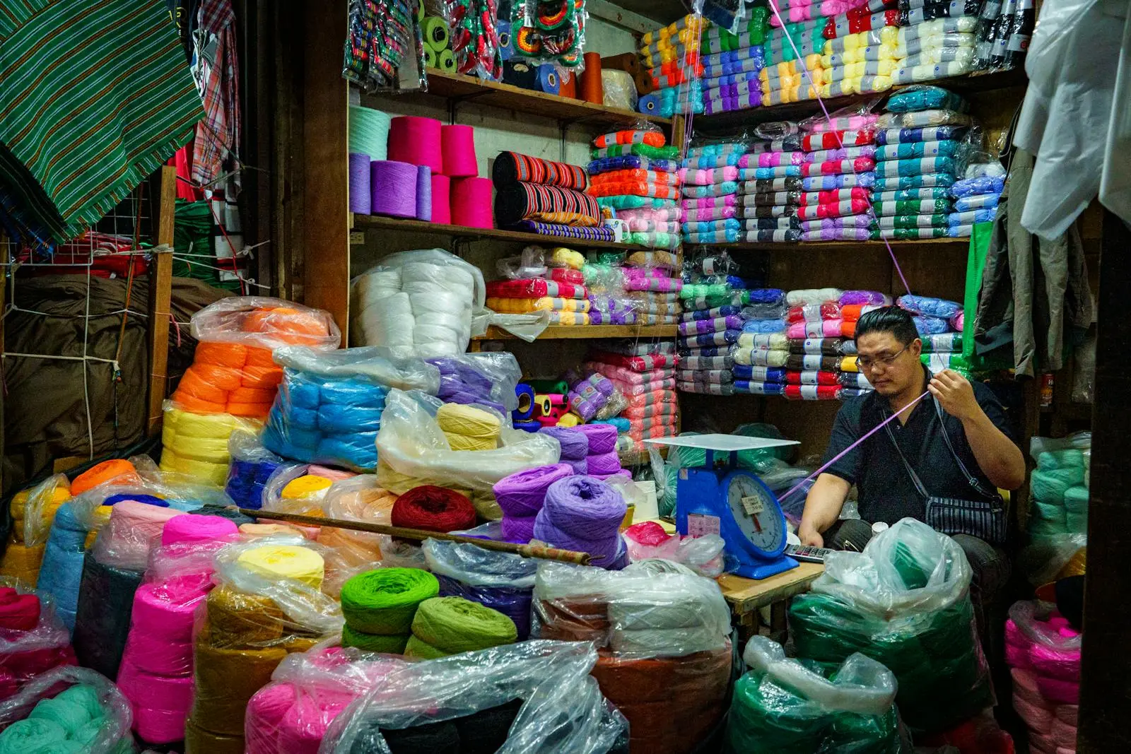 Vibrant yarn shop in Baguio, featuring colorful threads and a skilled artisan at work.