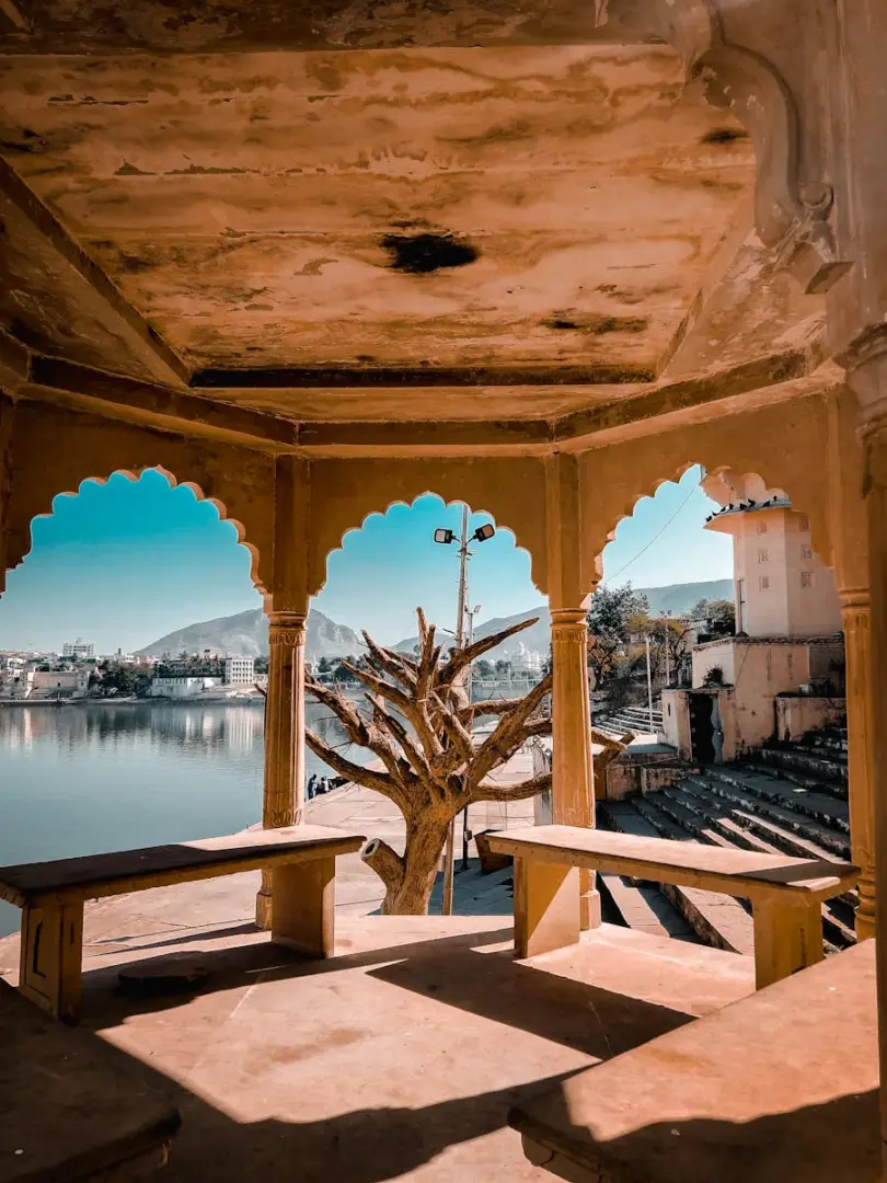 Capture of a rustic gazebo by a tranquil lake with a scenic view of the town in the distance.