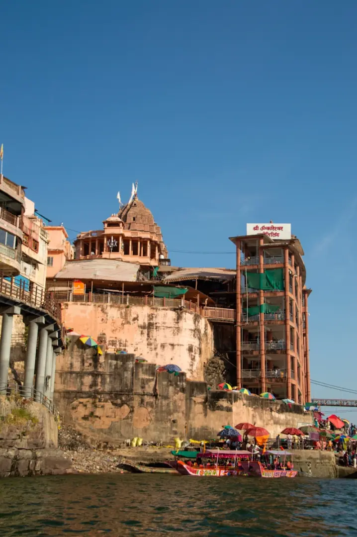 Buildings on a riverbank with colorful boats below.