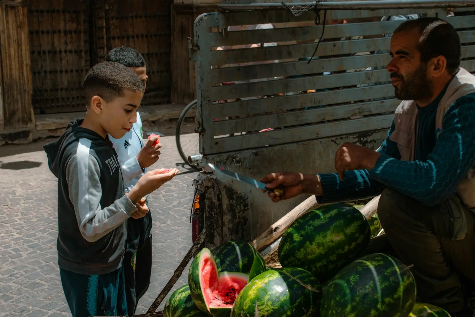 A boy buys watermelon from a street vendor.