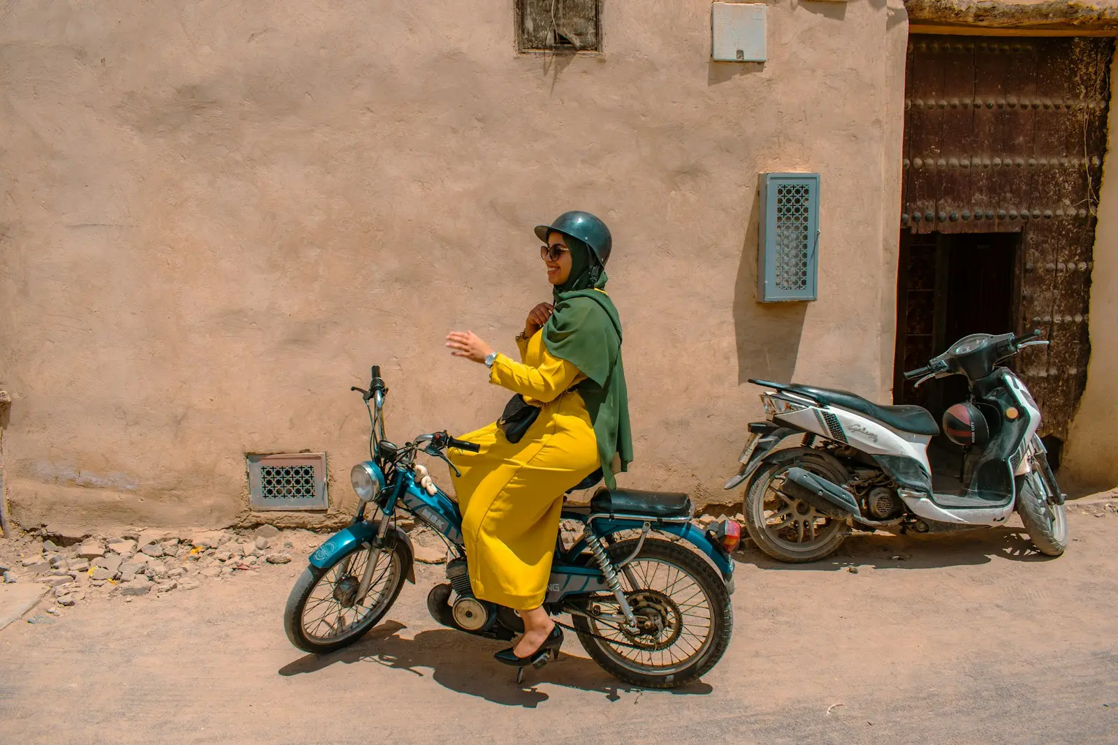 Woman rides a scooter in the sunny street.