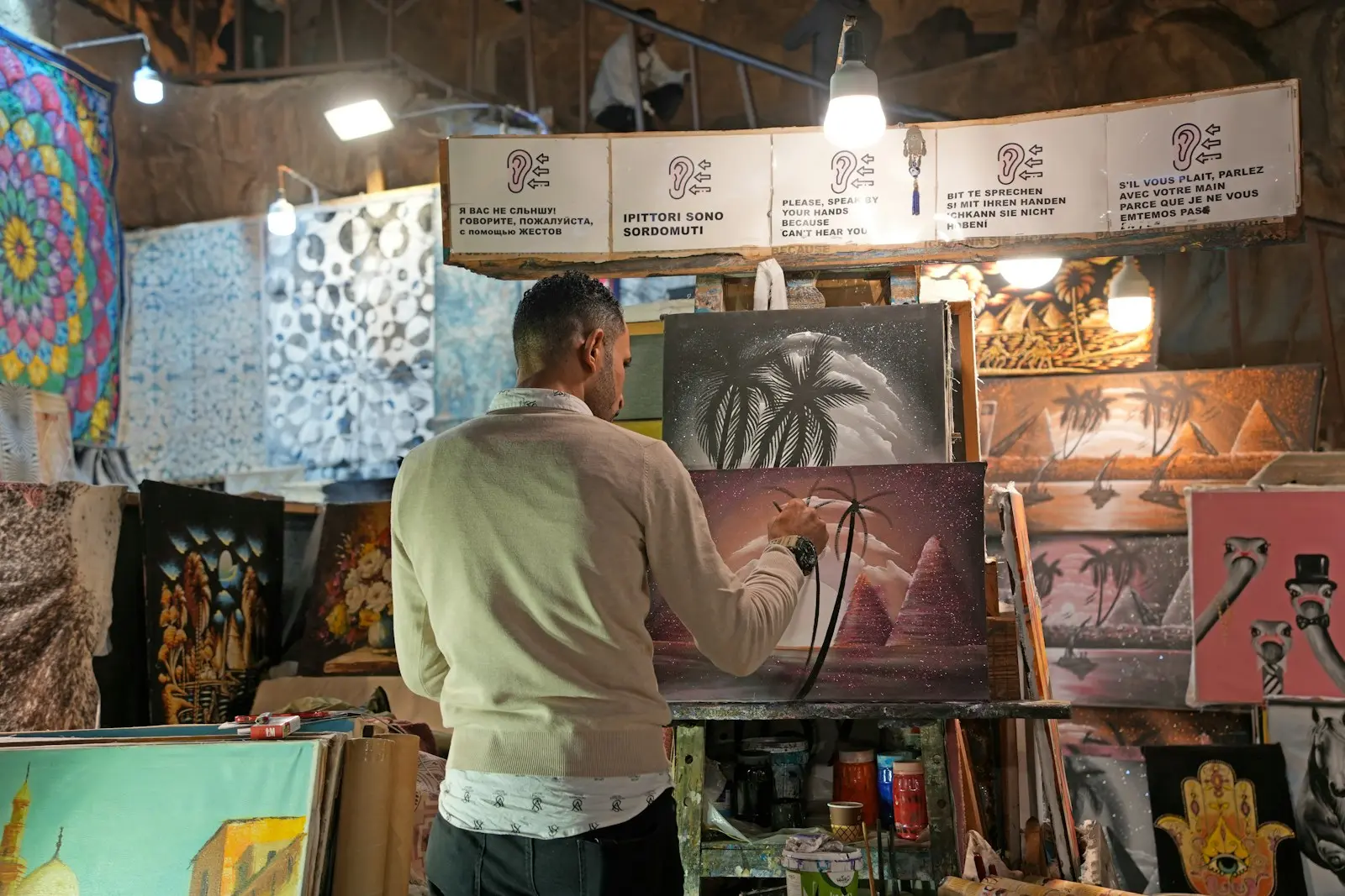 A man standing in front of a display of paintings