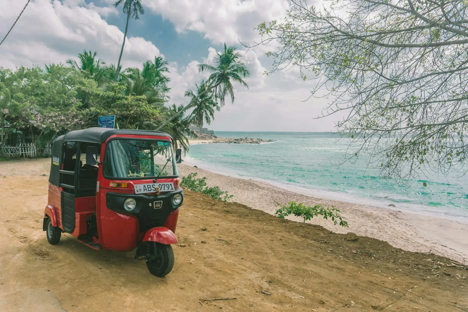 Prenájom tuk tuku na Srí Lanke 7 A small red car parked on the side of a beach