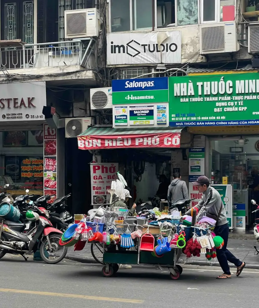 Street vendor selling various items from a cart.