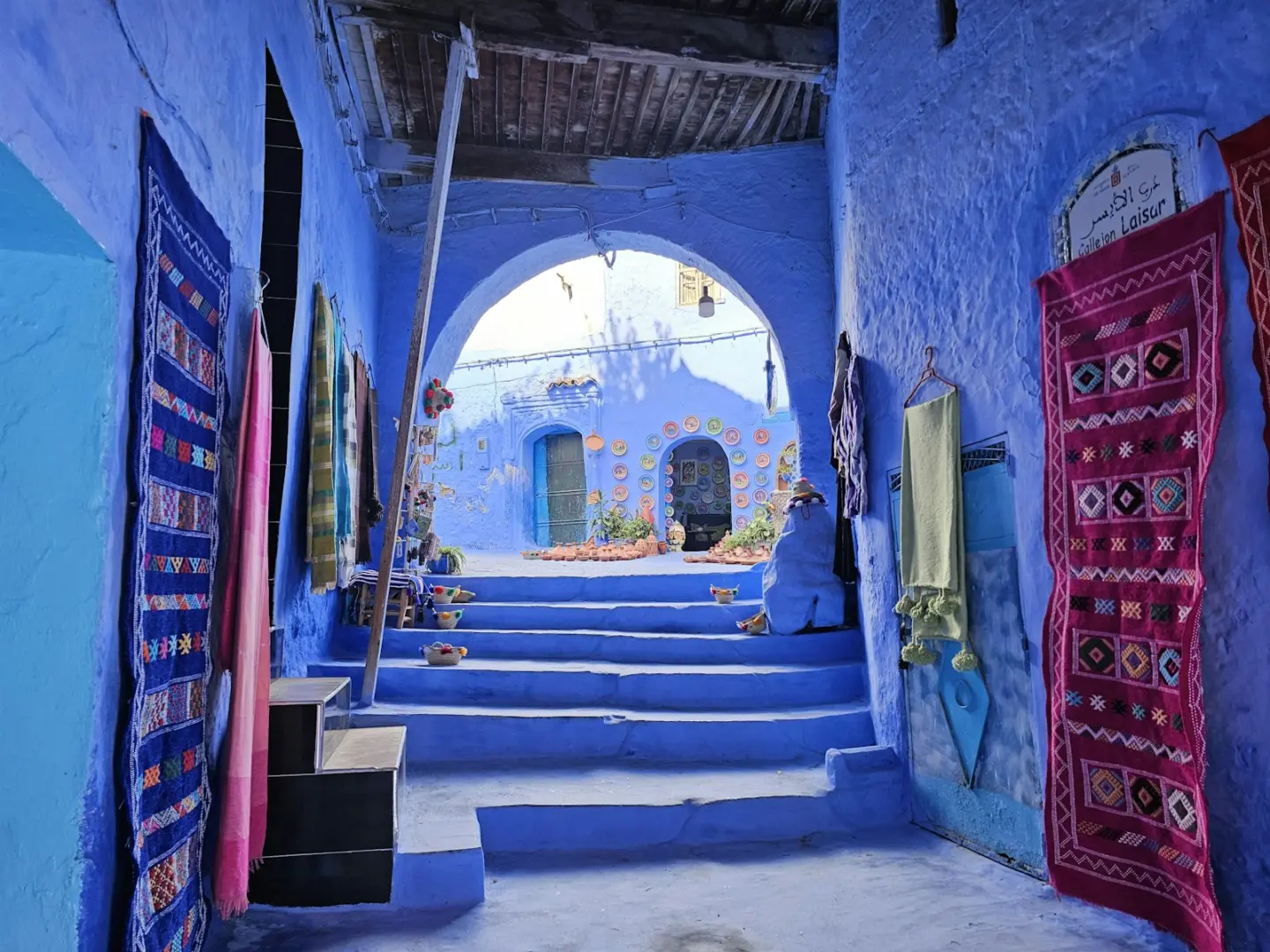 Blue alley with stairs and hanging rugs