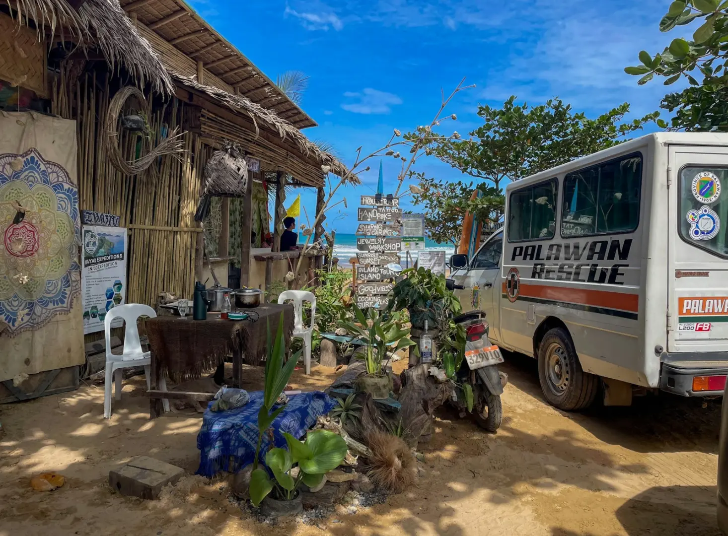 A tropical beach shack sits by a van.