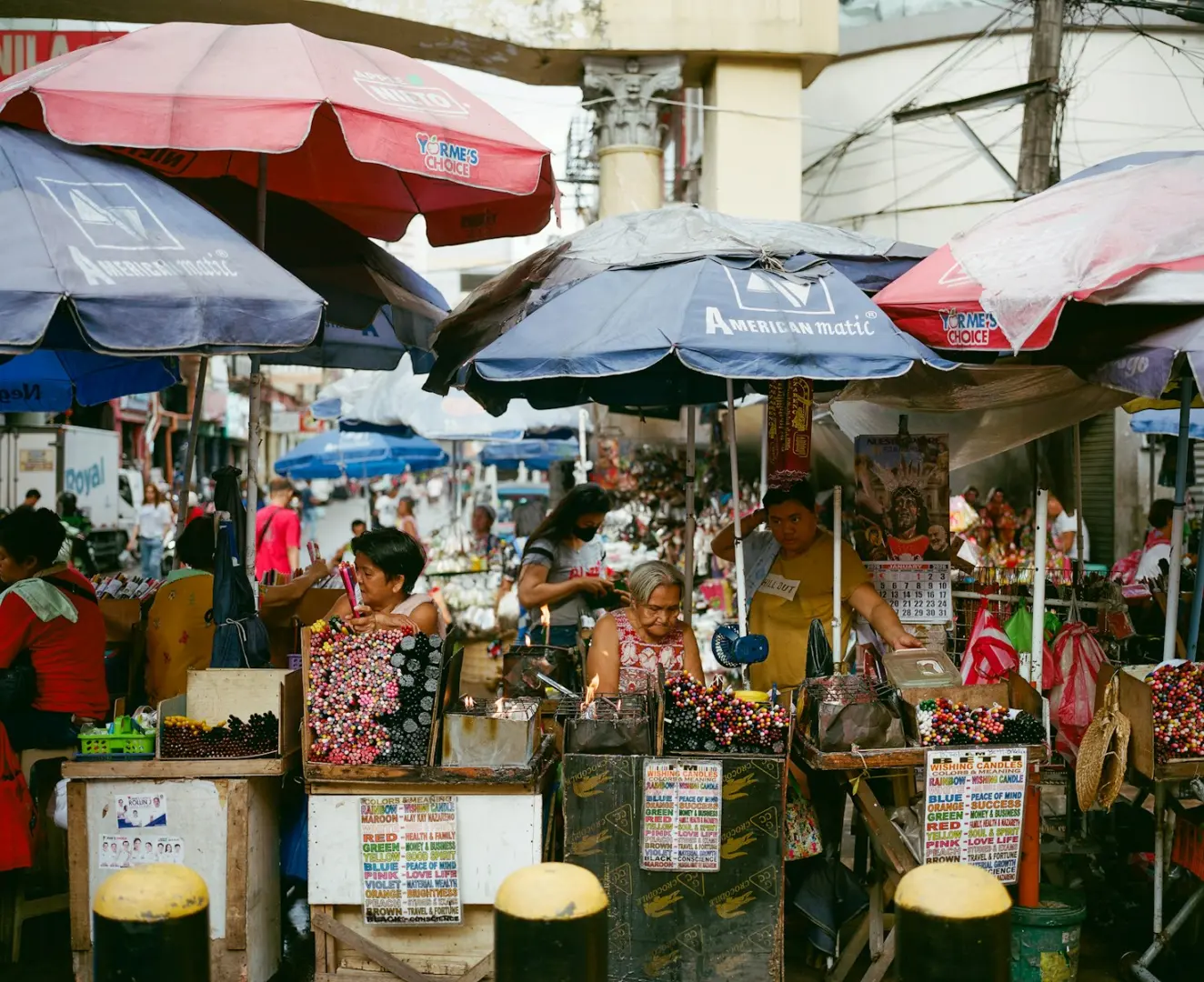 Busy outdoor market with vendors under umbrellas.