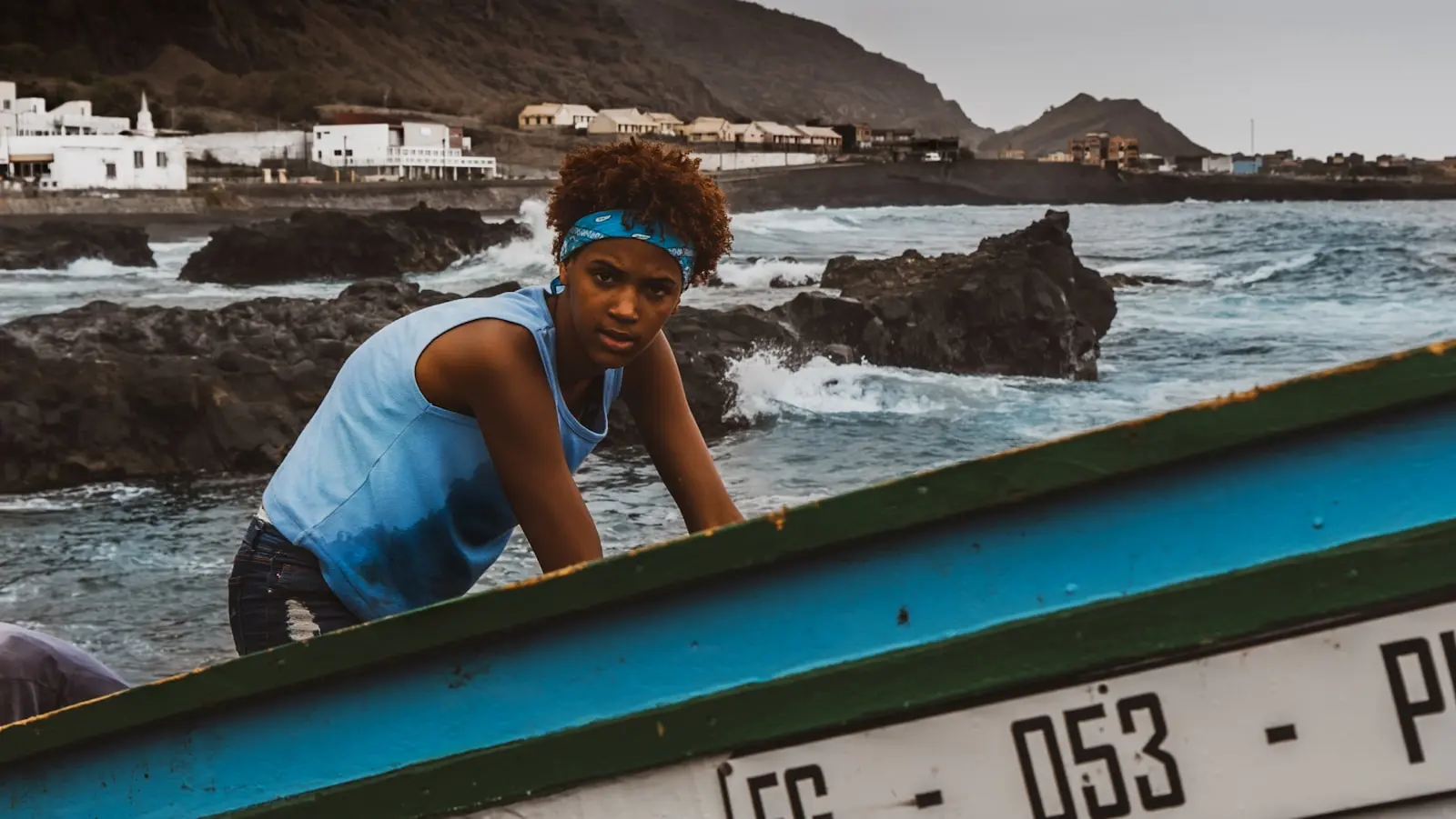 woman in blue tank top sitting on green boat during daytime