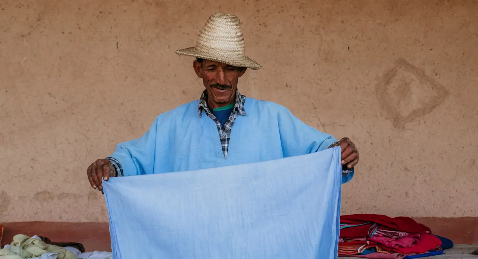 A man holds up a light blue piece of fabric.