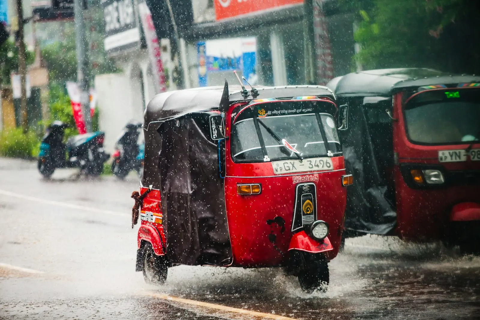 Prenájom tuk tuku na Srí Lanke 8 A red tuk-tuk drives through heavy rain.