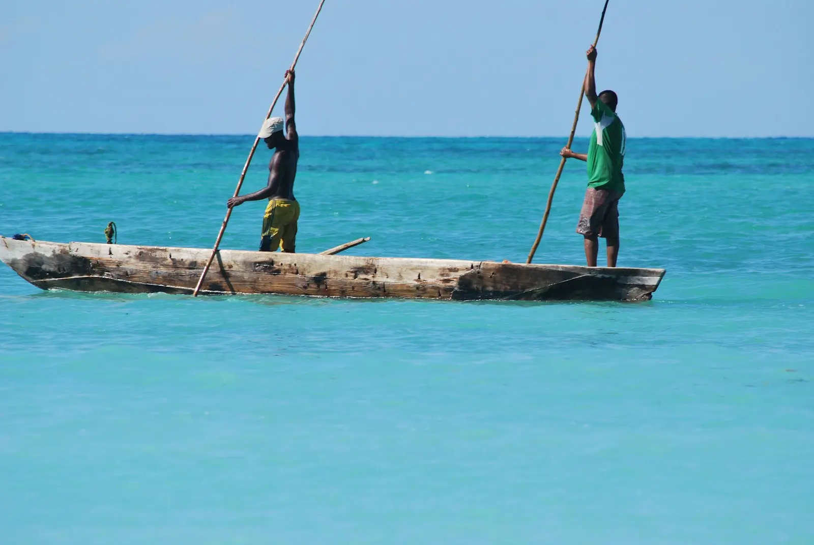 Two men fish from a boat in the ocean.