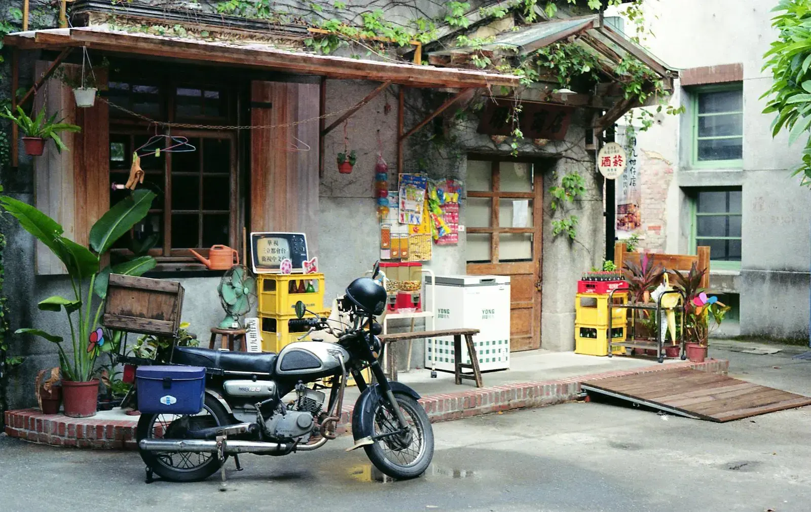 Vintage scooter parked in a rustic Taipei alleyway with plants and old architecture.