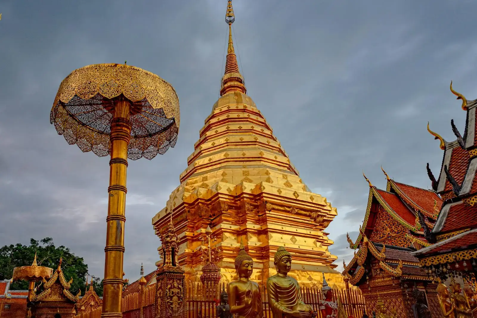 Stunning view of the golden Wat Phra That Doi Suthep pagoda under cloudy skies in Chiang Mai, Thailand.