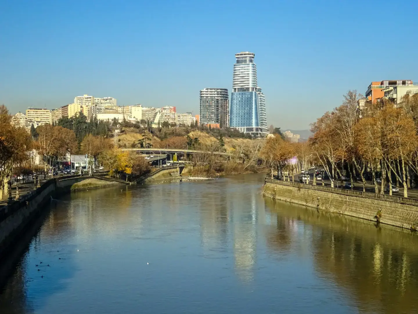 River flows through a city with modern buildings.