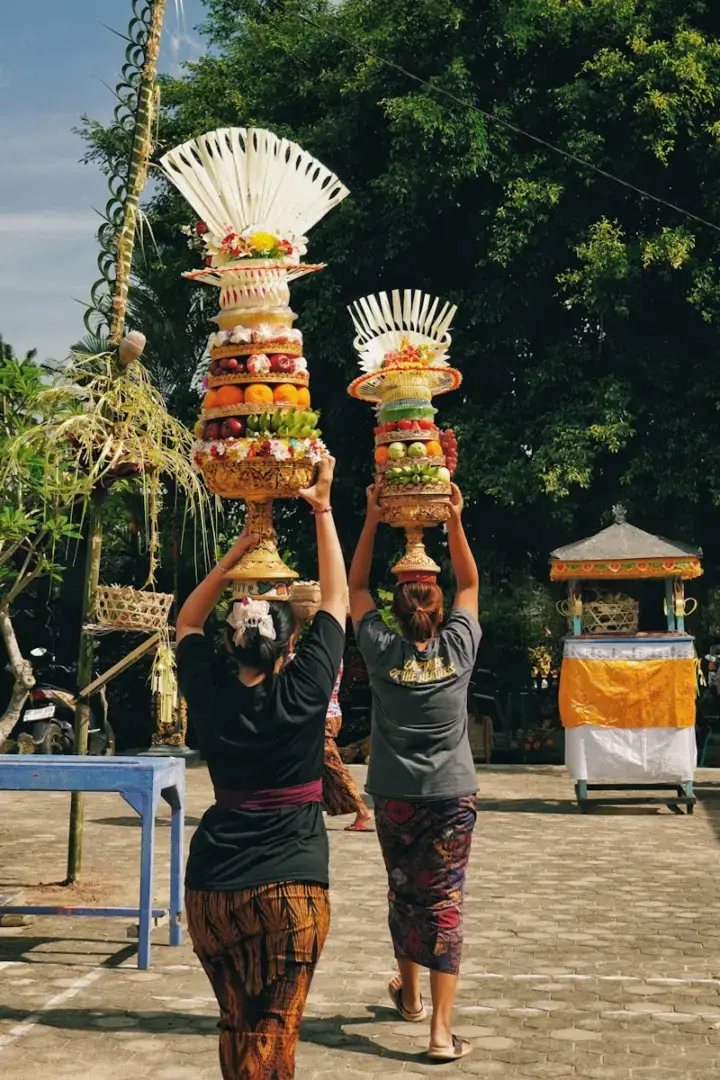 Two people carrying offerings on their heads