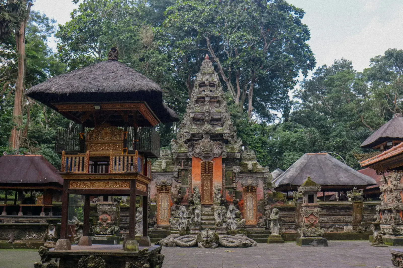 Ornate balinese temple complex surrounded by lush green trees.
