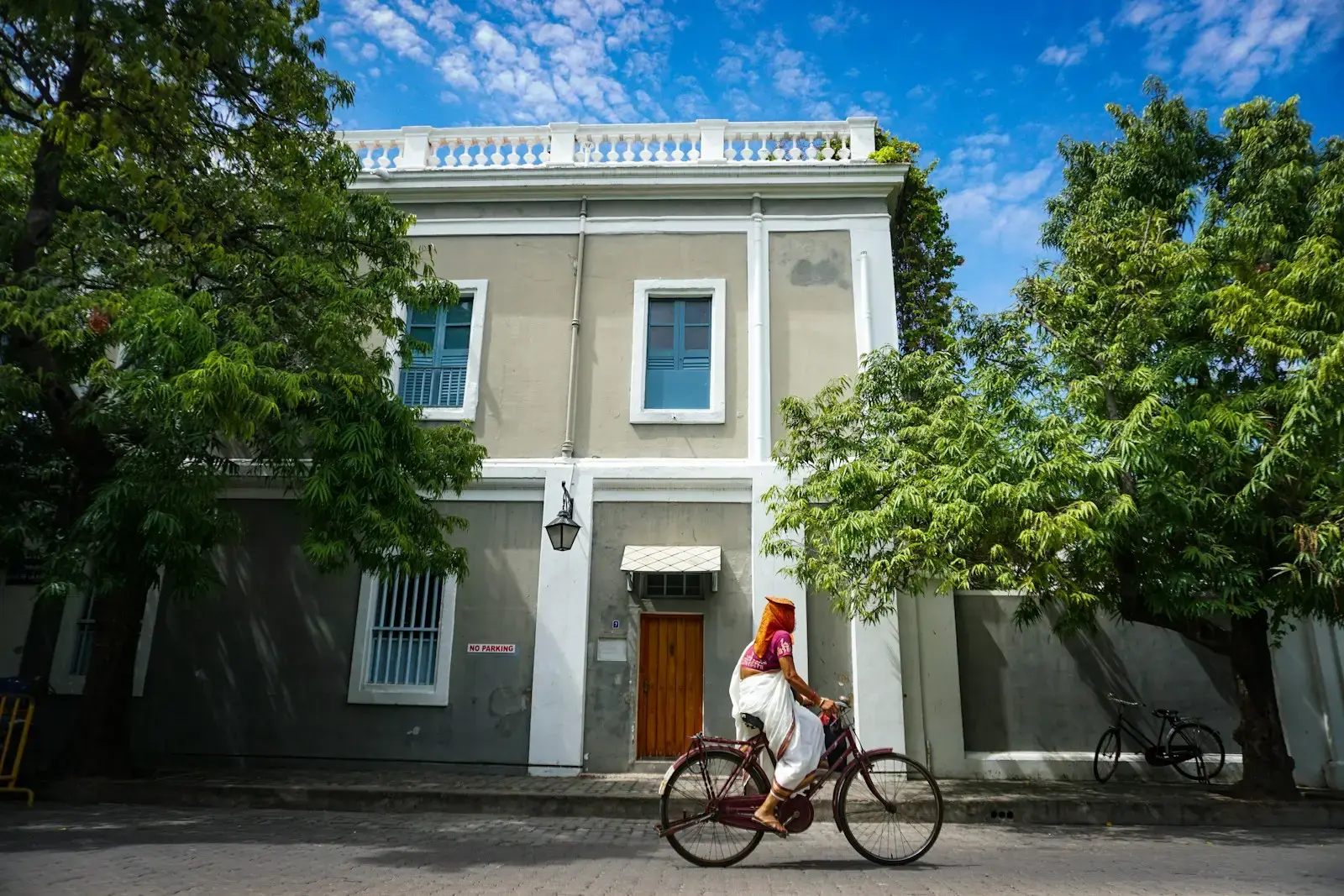 Photo by photoloord Anu man in white shirt riding on bicycle near white concrete building during daytime