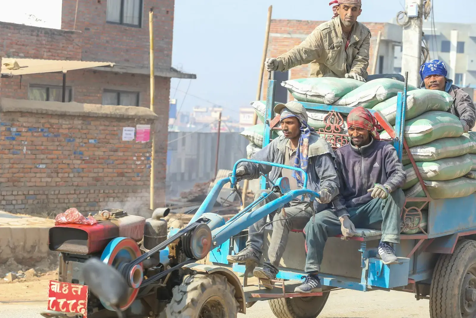 Workers ride on a trailer pulled by a small tractor.