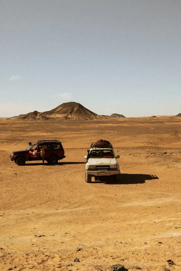 Photo by Jorge Garcia a couple of cars parked in the middle of a desert