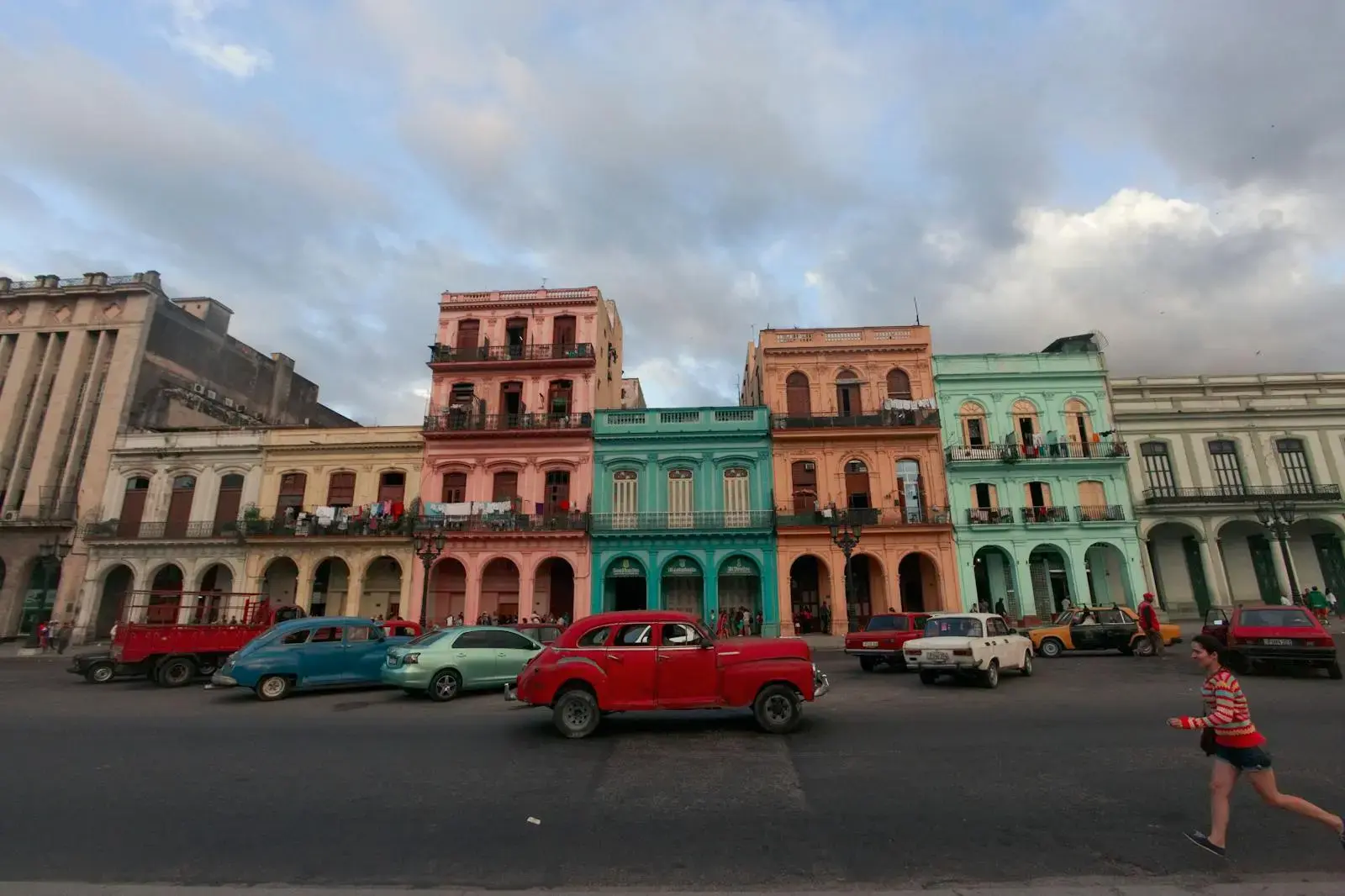 Vibrant Havana street with classic cars and colonial architecture, lively urban atmosphere.