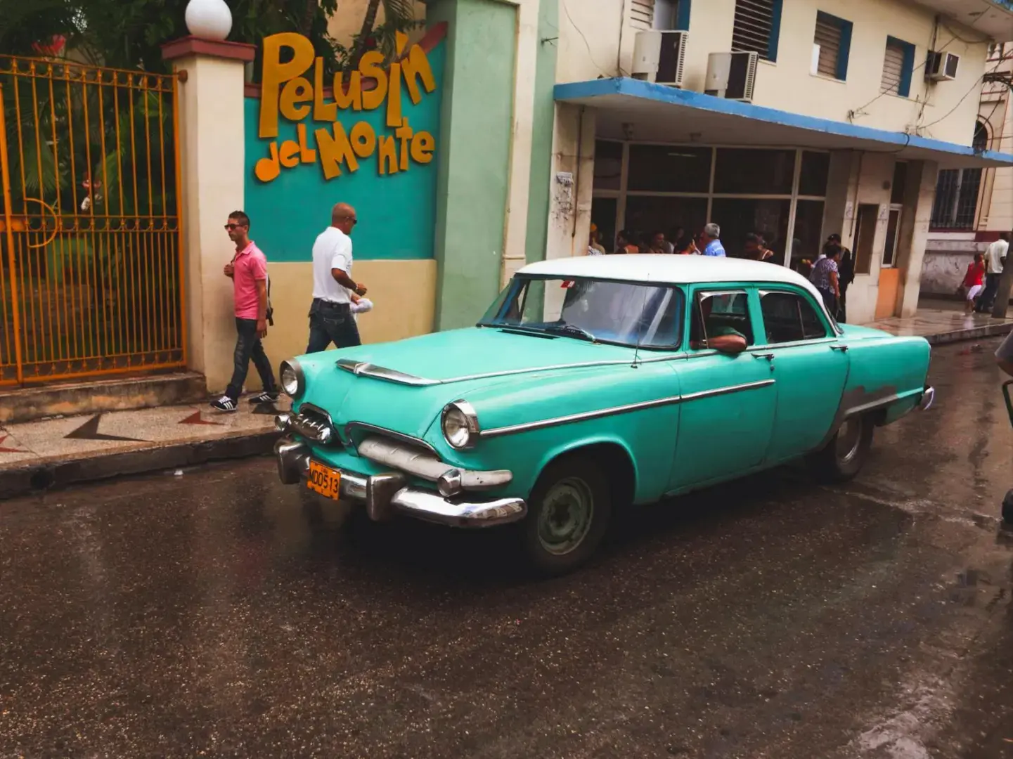 A classic vintage car parked on a wet street in Havana, Cuba, after a rain shower.
