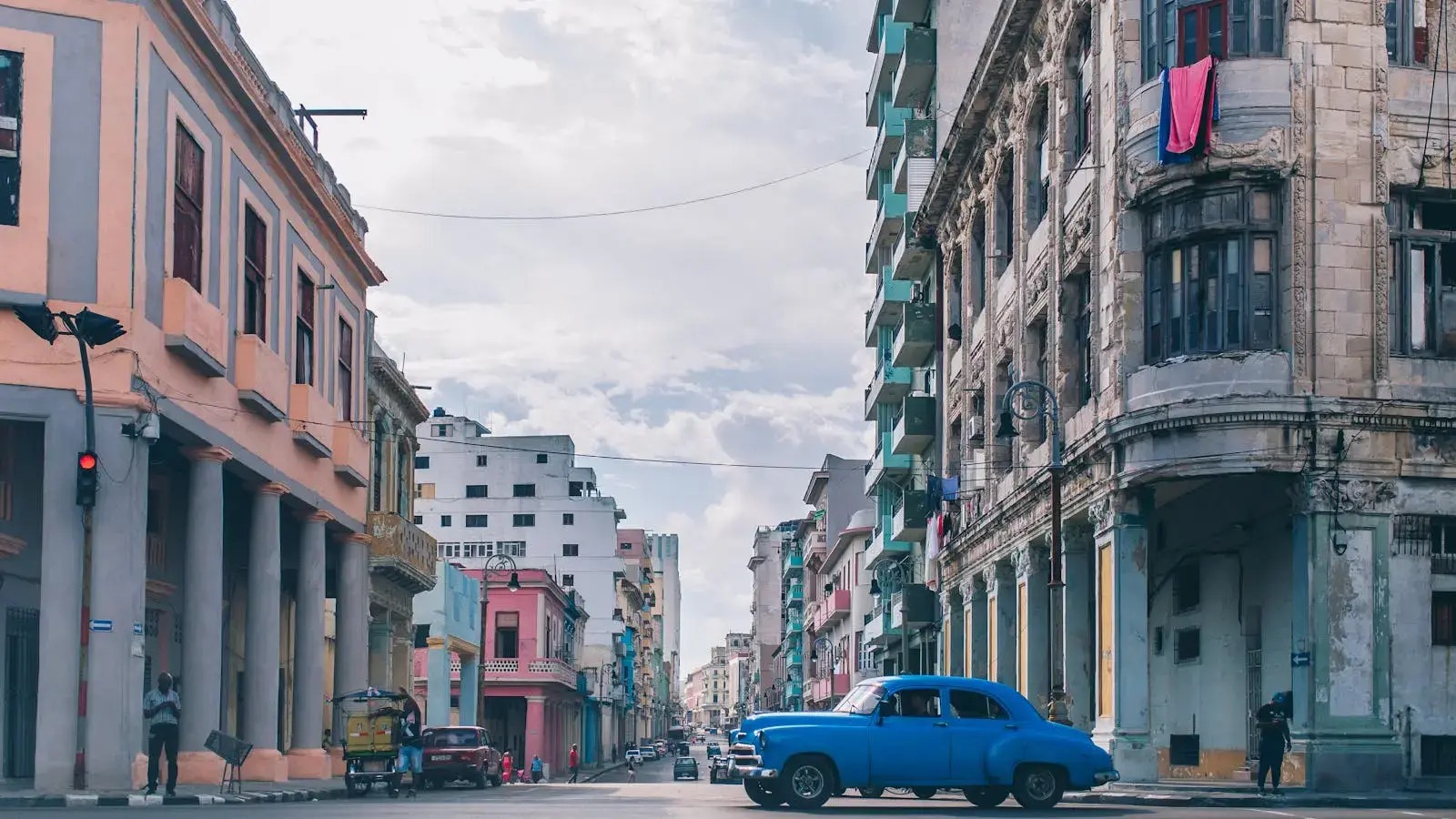 Captivating urban scene in Havana with vintage architecture and classic blue car under a clear sky.
