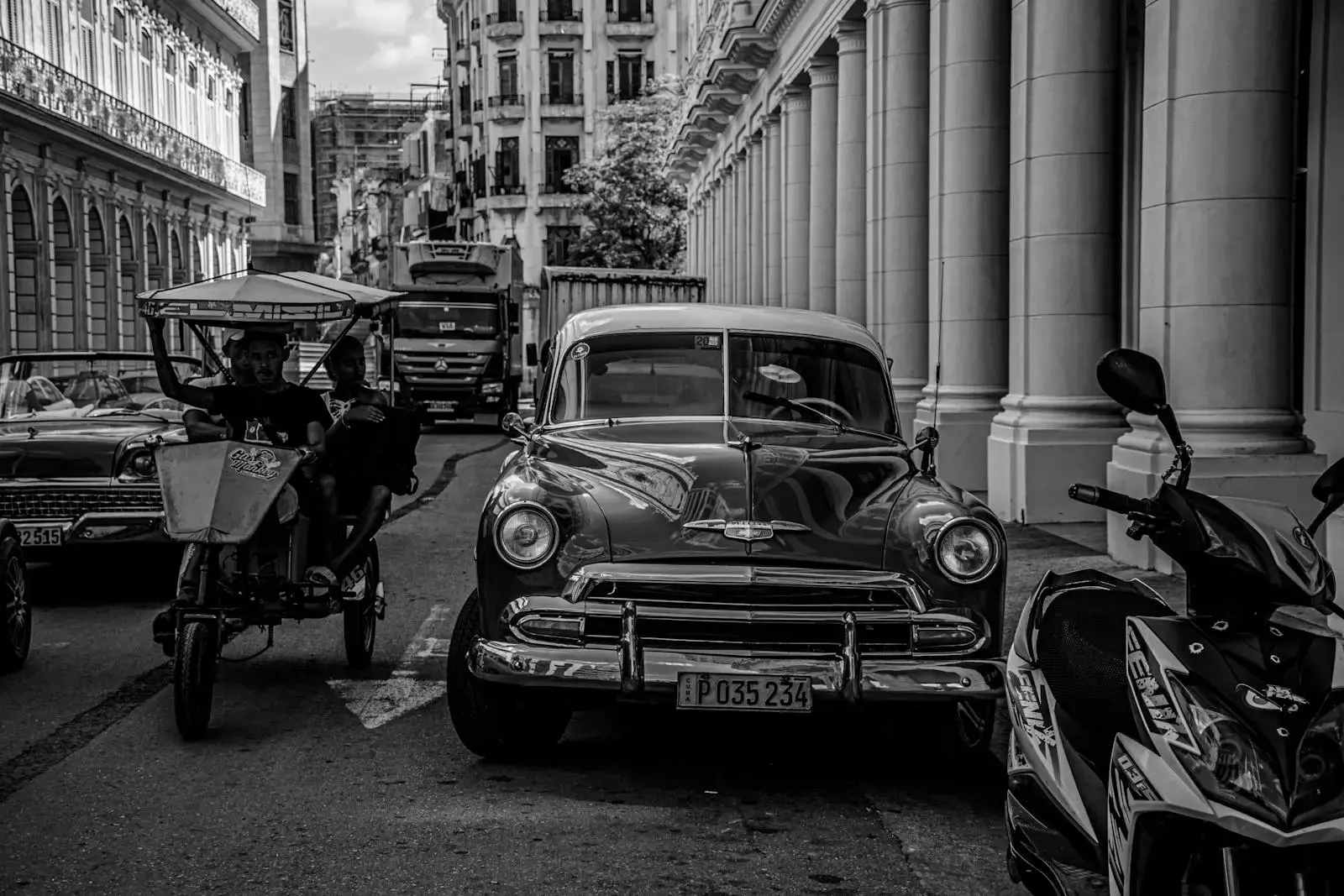 Black and white photo of classic cars on a bustling street in Havana, Cuba.