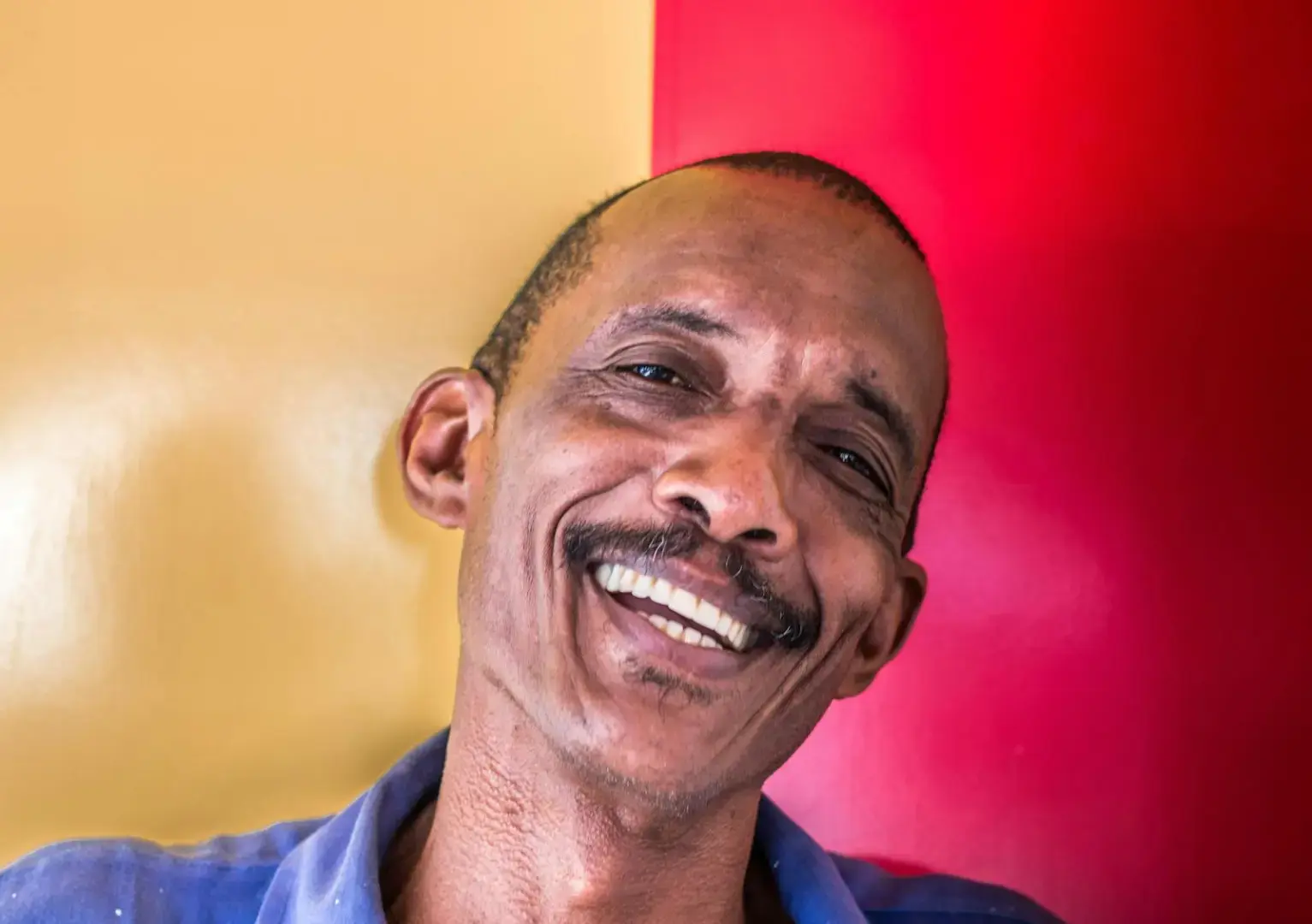 Cheerful man with mustache smiling against vibrant background in Havana, Cuba.