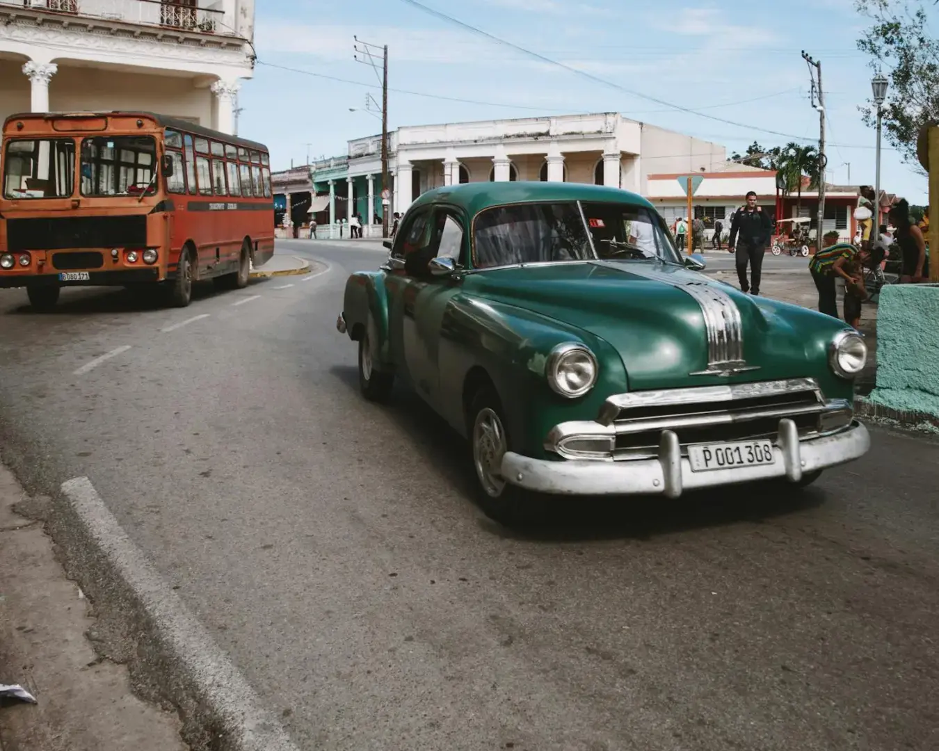 Photo by Mehmet Turgut Kirkgoz Classic Pontiac and retro bus on streets of Cuba, embodying nostalgic charm.