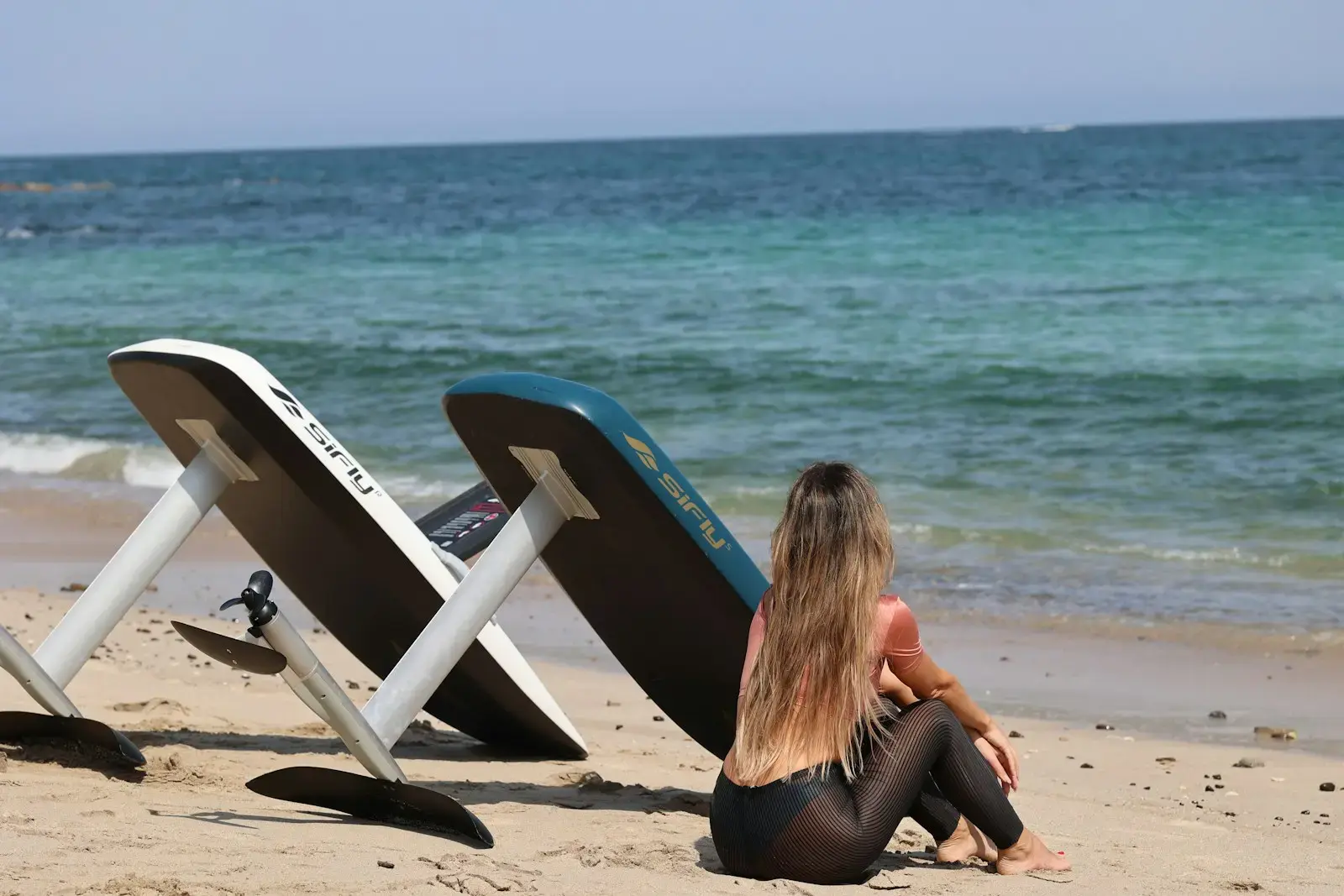 Photo by Kristina Nikitina A woman sitting on a beach next to a chair