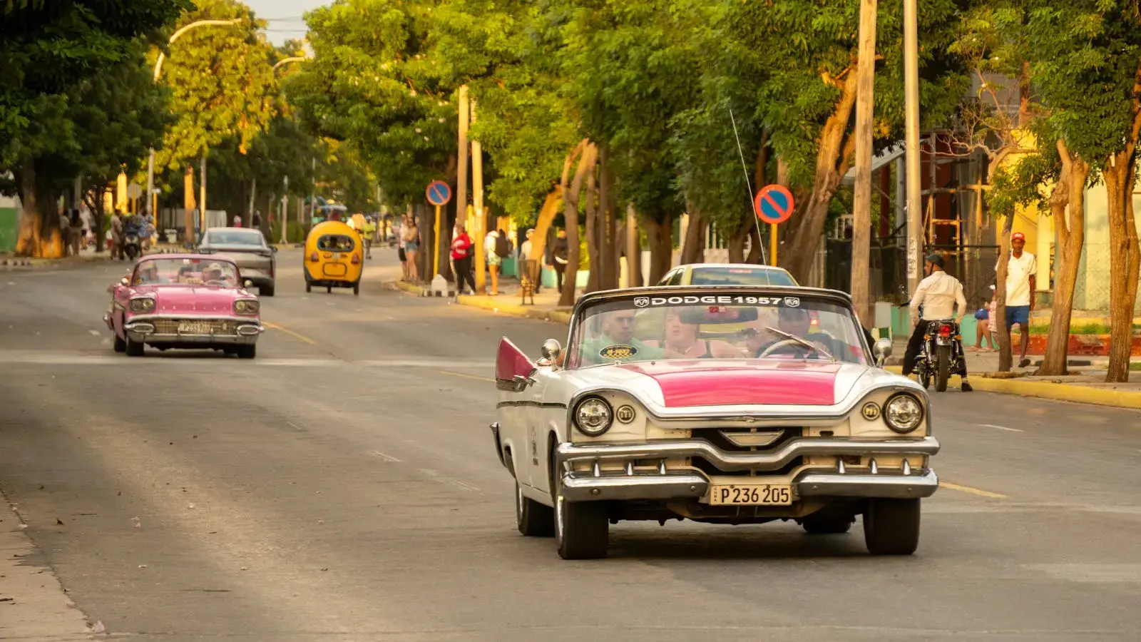 Vintage cars cruising down a sunlit street in Varadero, Cuba, exuding nostalgic charm.