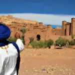 person in white long sleeve shirt and blue hat standing on brown sand during daytime