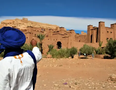 person in white long sleeve shirt and blue hat standing on brown sand during daytime