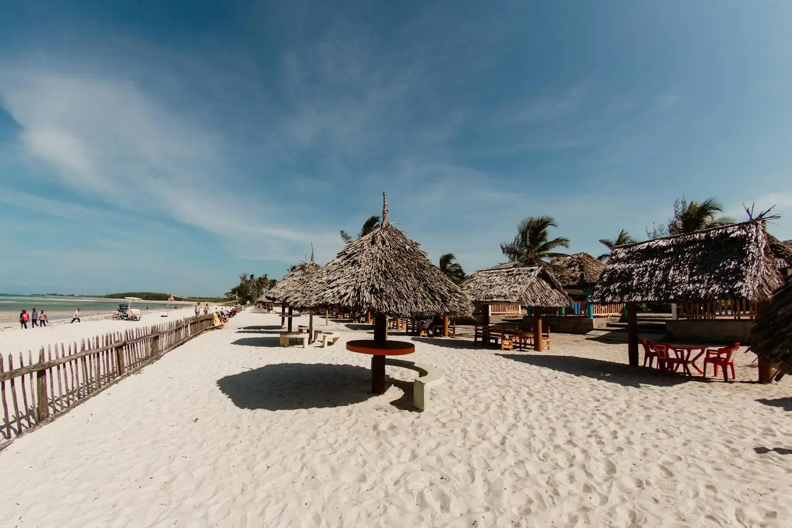 Photo by Og Mpango Serene tropical beach huts on a sunny white sand beach in Dar es Salaam, Tanzania.