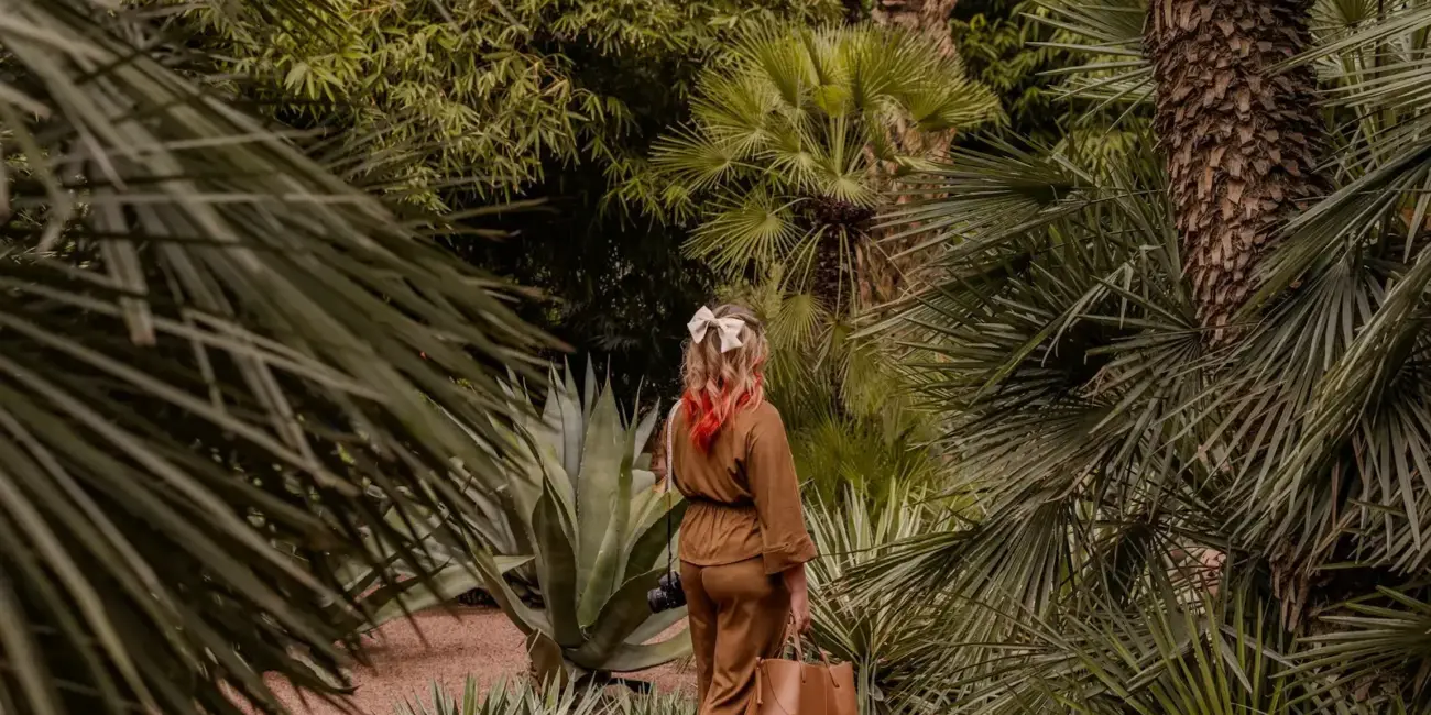 Woman walking through a lush green botanical garden.