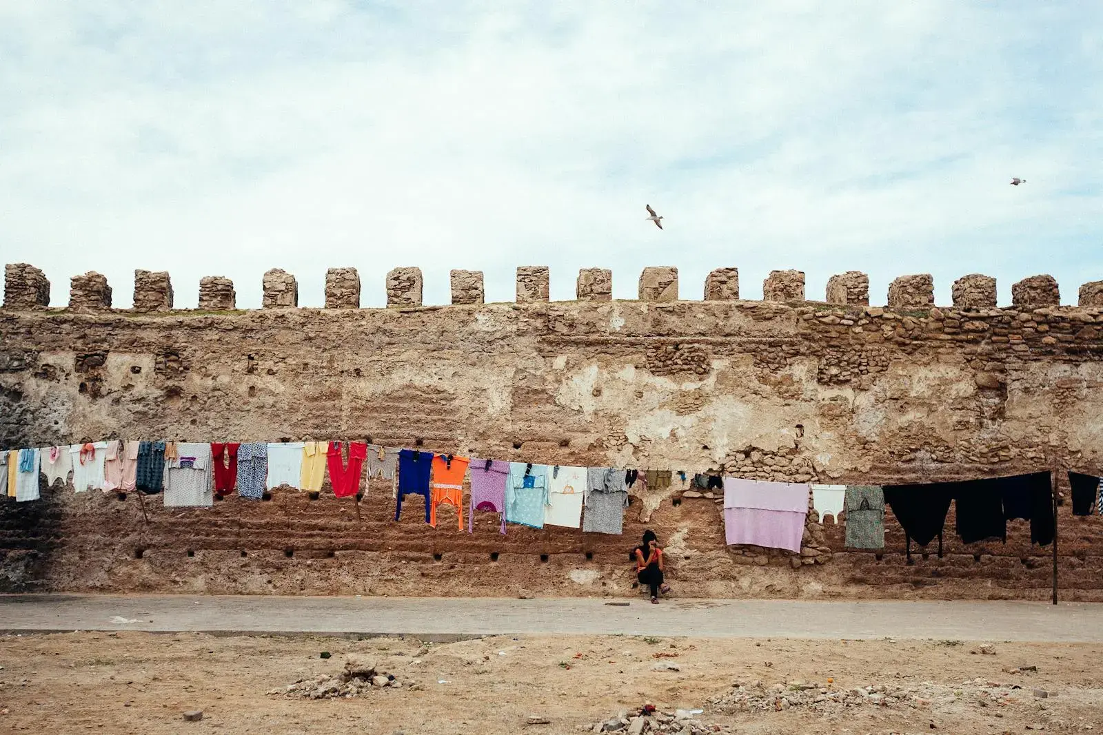 Photo by Dasha Klimova Colorful laundry hanging on ancient city walls in Essaouira, Morocco, showcasing daily life.