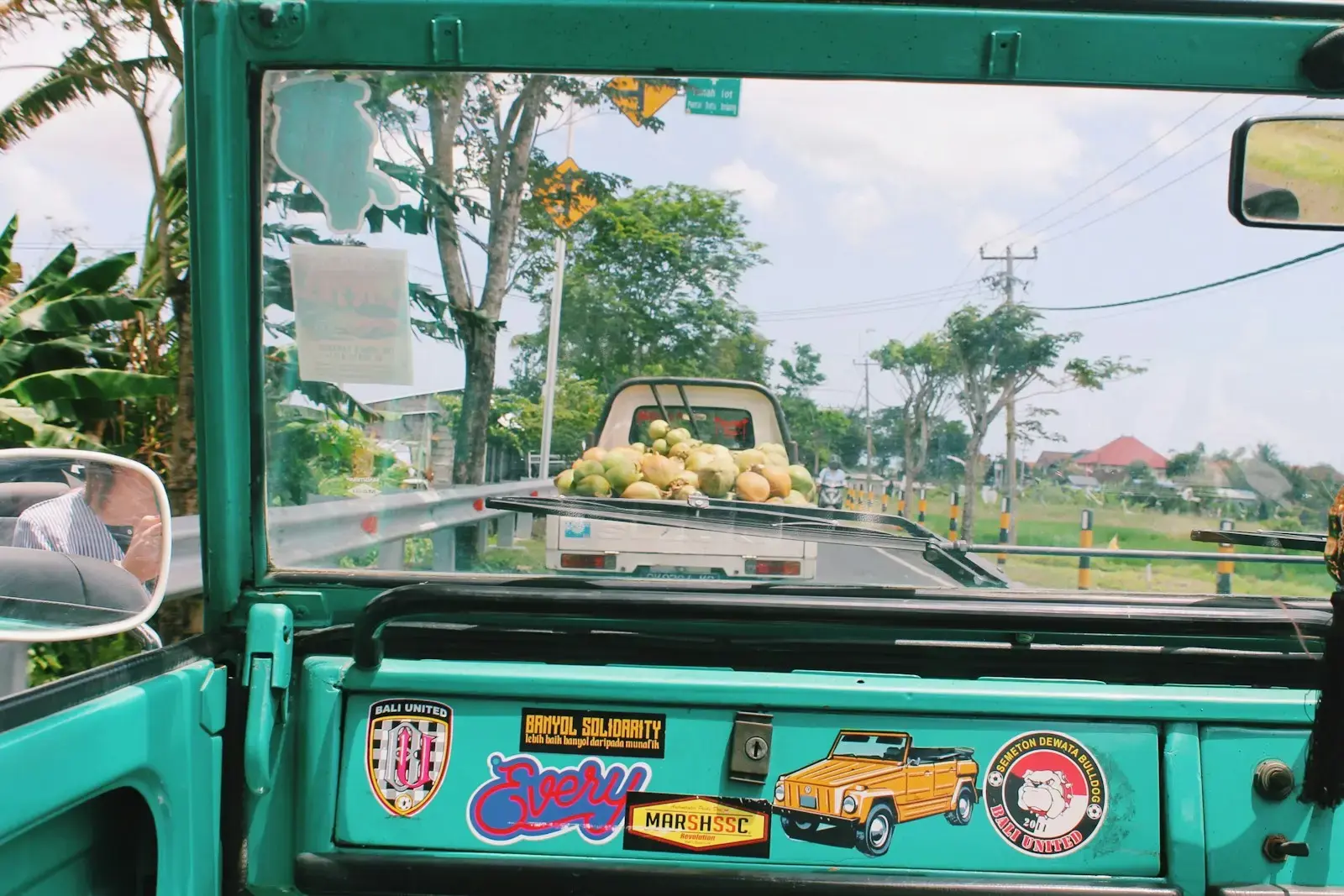 Photo by Elise Zimmerman drop side truck carrying coconuts passing on road during daytime