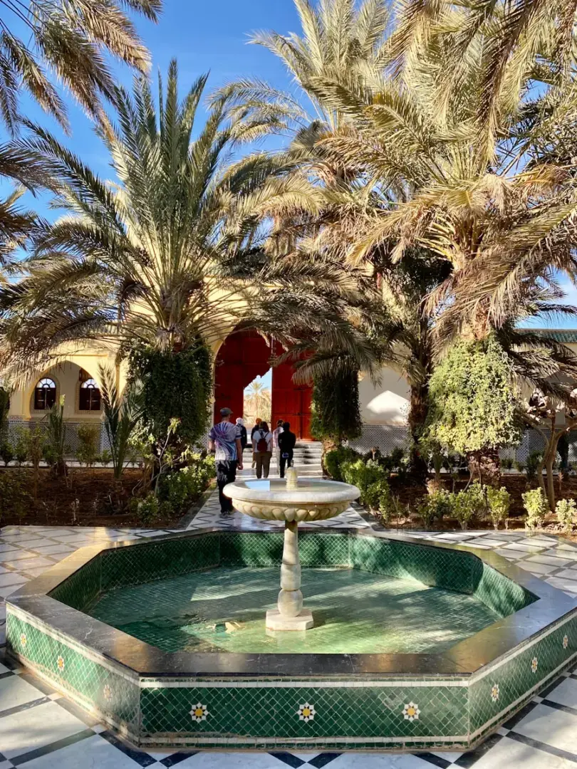 Photo by Jillian Amatt - Artistic Voyages a fountain surrounded by palm trees in front of a building