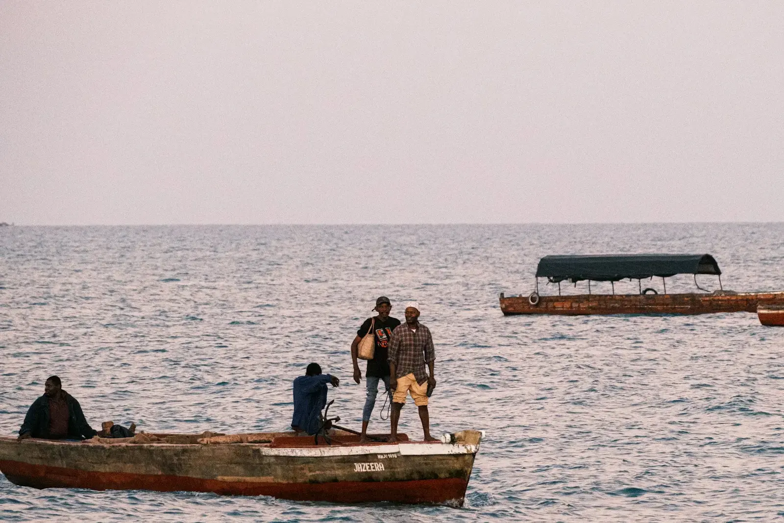 a group of men standing on top of a boat in the ocean
