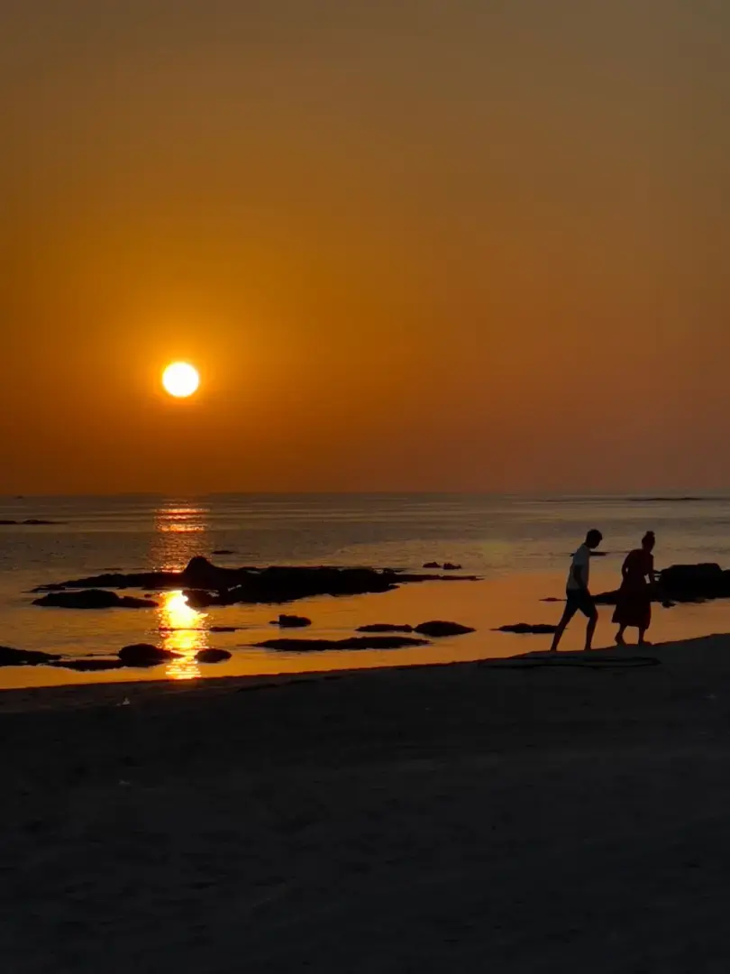 Photo by Massimo Virgilio Two people walking on a beach at sunset