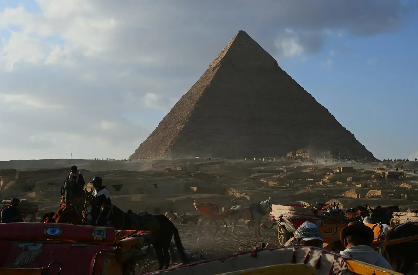 The great pyramid of giza with people and horses.