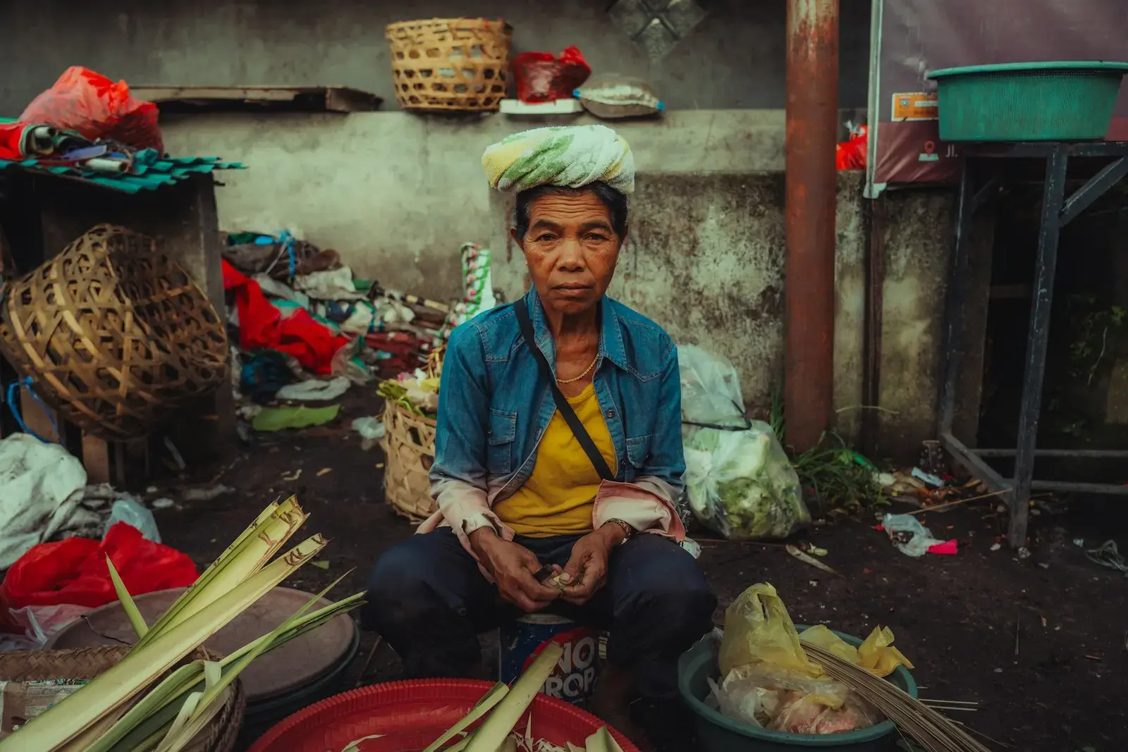 A woman sits amongst market goods.