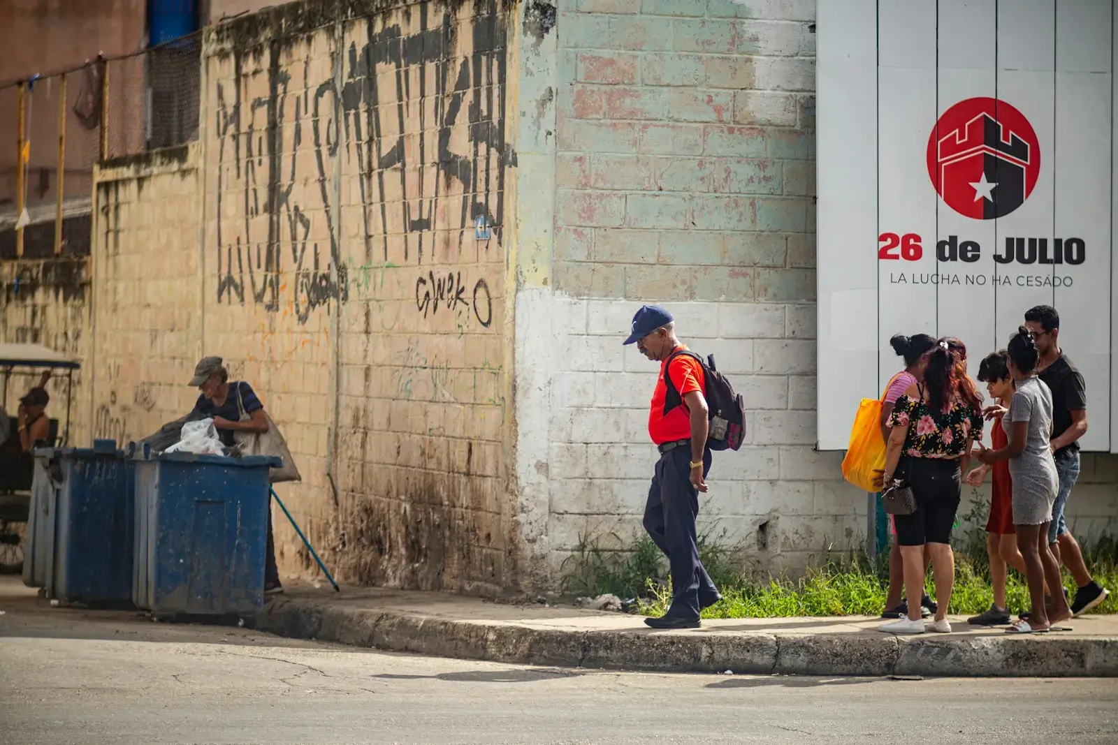People walk past a mural on a city street.