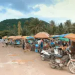 Outdoor market with stalls, motorcycles, and people