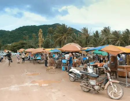 Bezpečnosť v Kambodži Outdoor market with stalls, motorcycles, and people