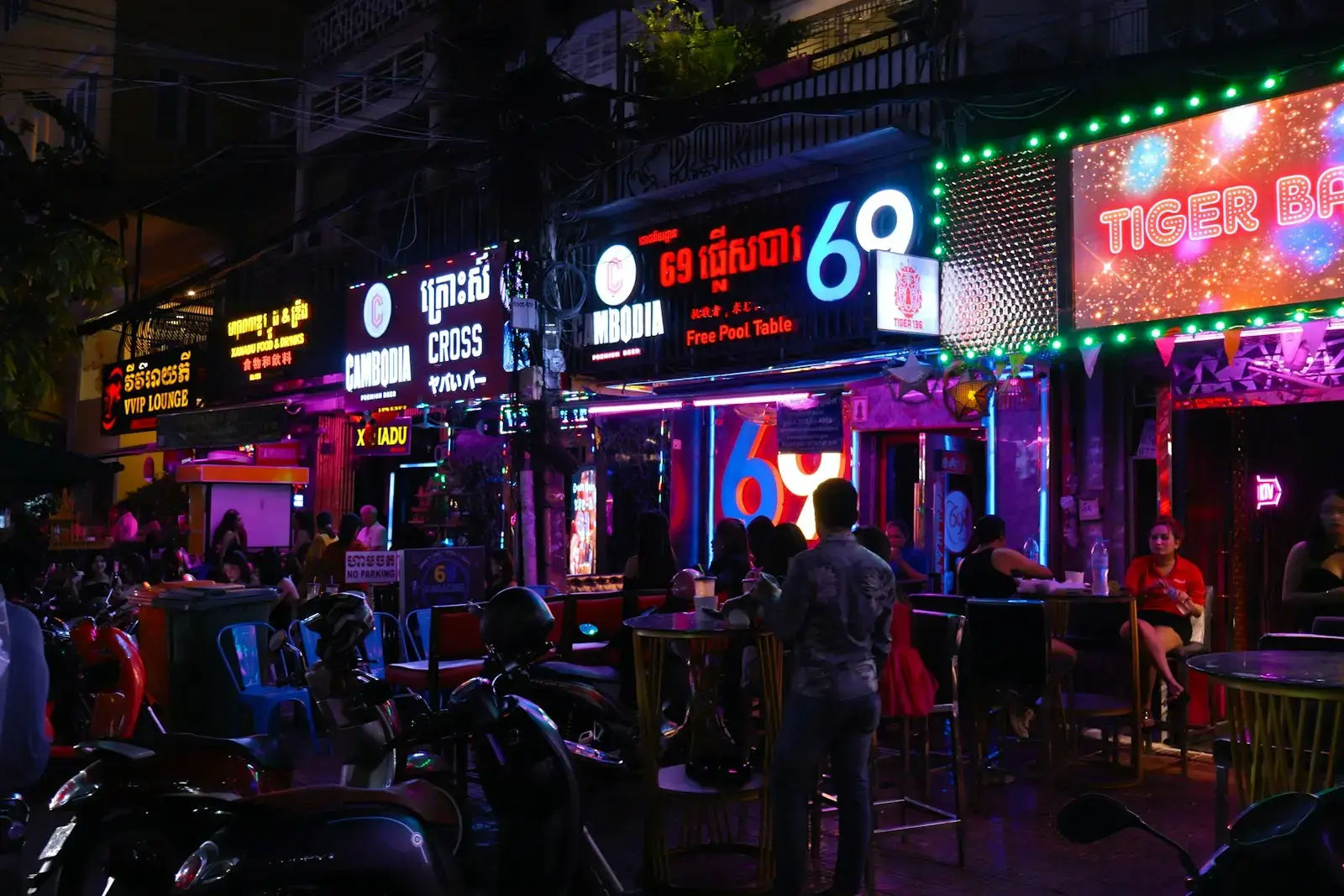 Photo by waa towaw Nightlife street with neon signs and bars.
