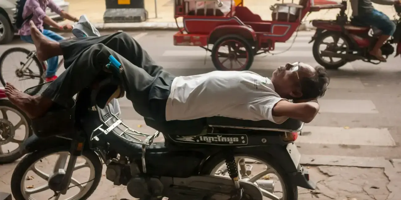 Man sleeping on a motorcycle on a city street